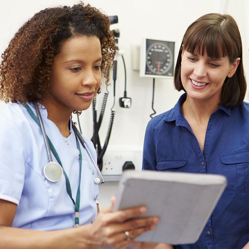 Nurse and administrator looking at computer tablet